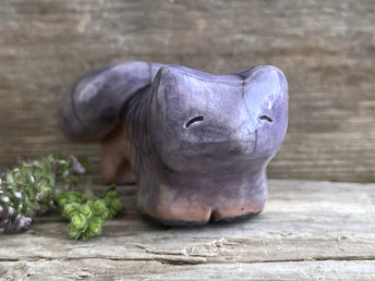 raku ceramic kitsune fox sculpture glazed in a top-to-bottom gradient of soft violet to peach. it has a kind, gentle face, and a tail curled over its back.