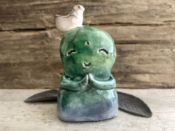 Shinto Jizo nature spirit guardian ceramic statue glazed in blue and green with a happy, smiley face, little praying hands, and a sweet white bird on his head.