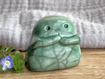 A sweet little kodama nature spirit ceramic guardian statue glazed in a soft forest green and with a lovely, gentle face and little arms.