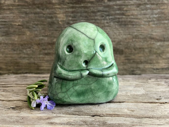 A sweet little kodama nature spirit ceramic guardian statue glazed in shades of green and with a lovely, gentle face and little arms.
