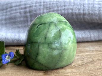 raku ceramic vaguely dome-shaped nature spirit sculpture. i suppose you could say it has a large tum? it's glazed in a spring green colour that almost seems to glow.