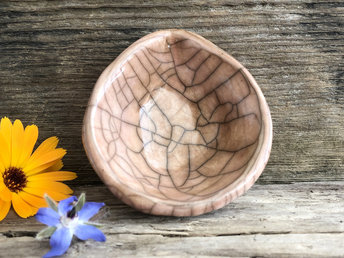 Raku ceramic offering bowl with a small spout. The bowl is glazed in soft peach and pink-brown with a beautiful raku crackle pattern.