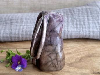 Raku ceramic usagi rabbit kami nature spirit glazed in a bottom-to-top gradient of warm brown to purple. Its ears are folded down its back, and it has a kind, gentle face.