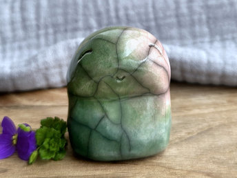 raku kodama kami nature spirit sculpture glazed in a top to bottom gradient of soft reddish pink to spring green. it has a gentle, kind face.