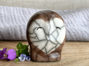 Ceramic raku owl kami nature spirit sculpture glazed mostly in soft brown with a white heart-shaped face. It has a very kind, friendly expression.