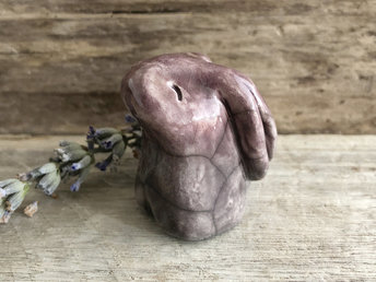 Small raku ceramic usagi rabbit kami nature spirit glazed in soft, muted violet and mauve colours. Her ears are folded down her back, and she had a kind, gentle face.