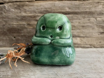 A sweet little kodama nature spirit ceramic guardian statue glazed in shades of green and with a lovely, gentle face and little arms.
