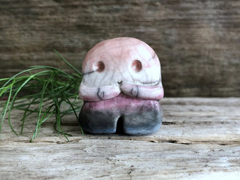 A sweet little nature spirit ceramic guardian statue glazed in the genderfluid flag pink, white, purple, black, and blue colours and with a lovely, gentle face and little arms. It has a small branch design carved up one side.