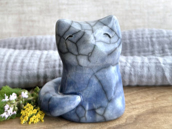 A Shinto Inari kitsune fox spirit ceramic raku statue glazed in a blue with beautiful raku crackles. Its tail is curled around the right side of its body, and it has a kind and very gentle face.