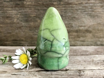 Raku ceramic nature spirit sculpture glazed in a gradiant from green to lighter green. It has a gentle face and a pointed head; it looks a little like a leaf bud.