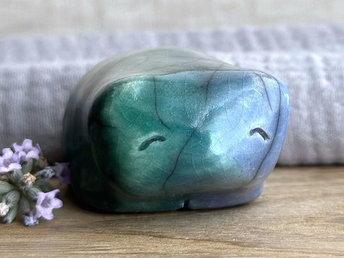 Raku ceramic bear kami sculpture glazed in forest green mostly on its left side and blue mostly on its right side. Where they overlap is a beautiful aqua colour. It has a kind, gentle face and is a little chonky.