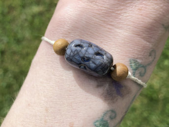 Blue raku ceramic cylindrical Shinto Jizo bead bracelet with two ethical sandalwood beads. It is strung on an adjustable eco-hemp cord. Jizo looks very happy and kind!