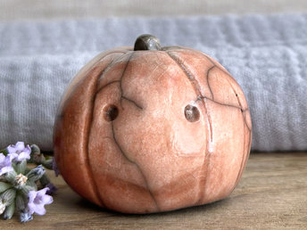 raku ceramic orange pumpkin nature spirit sculpture with a somewhat uncertain, worried look on its face. it has round eyes and a sort of v-shaped mouth and is quite cute. it has a cute little green-brown stalk on top.