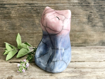 Raku ceramic sitting fox glazed in a gradient from blue to a mauve pink (bottom to top). It has a kind face, and its front is curved in with a place for your thumb.