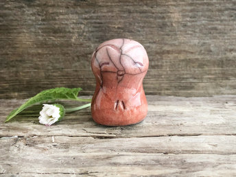 A smiley, loving, happy little Jizo Shinto raku ceramic sculpture talisman glazed in a gradient from red-orange to soft pink (from bottom to top) with a little heart around her face.