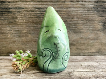 Raku ceramic sculpture of an elemental earth spirit being. It is very friendly, and it's glazed in a bottom-to-top gradient from forest green to spring green. It has Celtic spiral and plant carvings on its body.