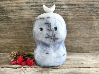A kodama nature and forest spirit kami ceramic raku sculpture glazed in a bottom-to-top gradient of soft blue to almost white. It has a gentle face, and a white crescent moon on its head.