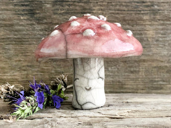 Cute raku ceramic fly agaric mushroom sculpture. Its stalk (where its smiley face is) is a creamy white colour, and its mushroom cap is a deep red with textured white bumps.
