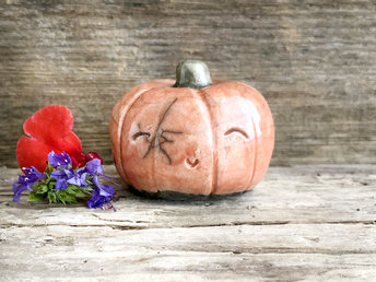 Raku ceramic orange pumpkin nature spirit kami sculpture with a very happy, smiley face.