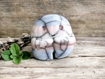A sweet little nature spirit ceramic guardian statue glazed in the transgender pink, white, and blue colours and with a lovely, gentle face and little arms. It has a small branch design carved up one side.