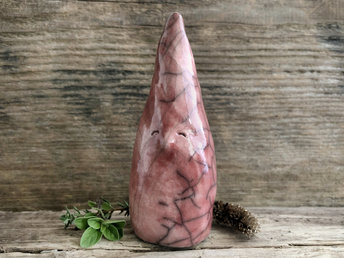 Raku ceramic sculpture of a tall, pointy gnome. He is very friendly and glazed in a warm, soft red colour.