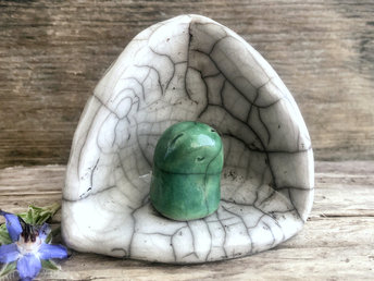 A Shinto kodama nature spirit kami of forests and trees in his own little kamidana shine. The kodama has a very sweet face and is glazed in green. The shrine is white with beautiful raku patterns and vaguely egg-shaped.