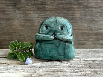 A sweet little kodama nature spirit ceramic guardian statue glazed in forest green and with a lovely, gentle face and little arms.