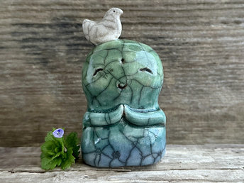 Shinto Jizo nature spirit guardian ceramic statue glazed in a bottom-to-top gradient of blue and green with a happy, smiley face, little praying hands, and a sweet white bird on his head. There are tiny dark grey spiderweb patterns in the glaze, in addition to the normal raku crackles, from where raindrops fell on it.