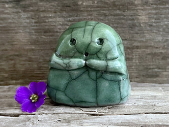 A sweet little kodama nature spirit ceramic guardian statue glazed in shades of green and with a lovely, gentle face and little arms.