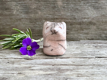 very small raku ceramic fox sculpture glazed in a peach colour. it has a gentle face with a cool raku crackle pattern on its forehead.