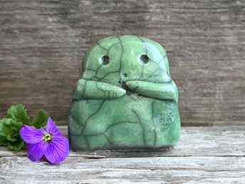 A sweet little kodama nature spirit ceramic guardian statue glazed in shades of green and with a lovely, gentle face and little arms.
