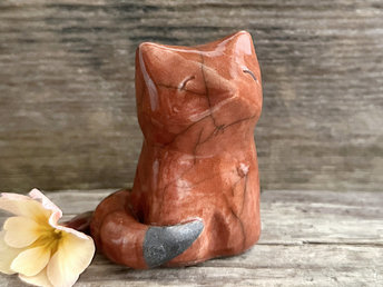 A wise and contented Shinto Inari sitting kitsune fox kami spirit ceramic raku statue glazed in a deep burnt-orange colour. The tip of its tail is unglazed black.