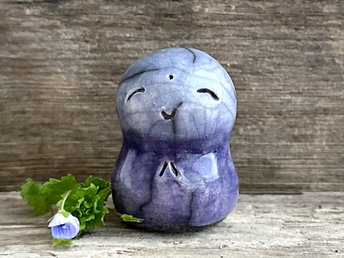 A smiley and loving Jizo Shinto raku ceramic sculpture talisman glazed in a bottom-to-top gradient of indigo-violet to blue. It has a kind, gentle face and is a wonderful smooth shape to hold in the hand.
