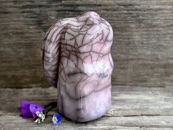 Raku ceramic usagi rabbit kami nature spirit glazed in a soft, pale pink-mauve colour with hints of violet. Its ears are folded down its back, and it has a kind, gentle face.