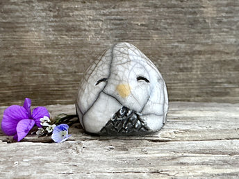 Raku ceramic little owl or owlet kami nature spirit statue glazed in white and grey-brown with gentle, smiling eyes and a little yellow beak.