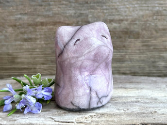 very small raku ceramic fox sculpture glazed in a soft mauve colour. it has a gentle face.