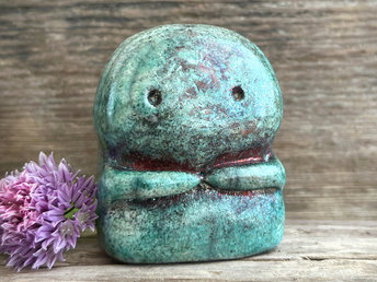 A kodama nature spirit ceramic guardian statue glazed in a turquoise and copper glaze. It has a wide face, two big eyes, and cute little arms.