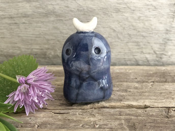 A sweet little nighttime kodama nature and forest spirit kami ceramic raku sculpture glazed in indigo blue with a gentle face and a crescent moon on its head.
