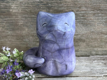 A calm and gentle Shinto Inari nighttime moon kitsune fox kami spirit ceramic raku statue glazed in a bottom-to-top gradient of violet to blue. Its tail is curled around the right side of its body, and it has a kind face.
