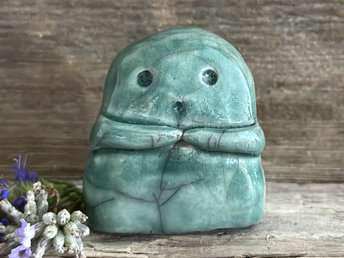 A sweet little kodama nature spirit ceramic guardian statue glazed in pale forest green and with a lovely, gentle face and little arms.