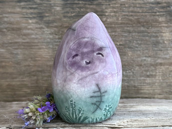 raku ceramic gnome spirit glazed in a bottom-to-top gradient of forest green to purple. it has a gentle, kind face, and there are flower and plant carvings around its base.