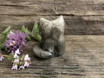 A gentle and peaceful Shinto Inari sitting kitsune fox kami spirit ceramic raku statue glazed in a gradient from light grey at his head to darker grey at his tail and feet.