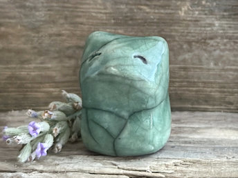 very small raku ceramic fox sculpture glazed in a soft forest-green colour. it has a gentle face.