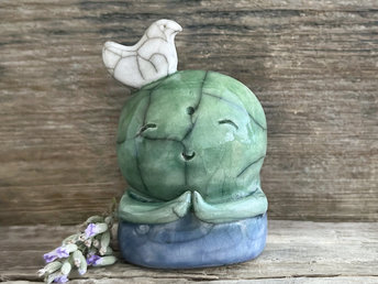 a shinto jizo nature spirit guardian raku ceramic sculpture glazed in a bottom-to-top gradient of blue to forest green to spring green. they have a happy, smiley face, little praying hands, and a sweet white bird on their head.