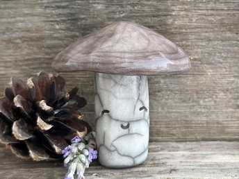 Cute mushroom raku ceramic sculpture with a very smiley face. Their stalk is glazed in creamy-white (this is where their face is) and their mushroom cap is brown.