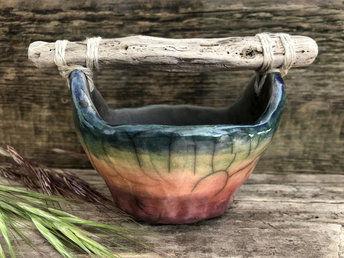 Raku ceramic bucket with a driftwood handle. The bucket is glazed in beautiful rainbow colours on the outisde, and the inside is left natural, unglazed black.