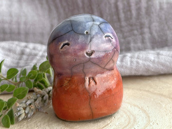 a smiley and loving Jizo Shinto raku ceramic sculpture talisman glazed in a bottom-to-top gradient of soft red-orange to mauve-purple to blue. he's a wonderful, smooth shape to hold in the hand.