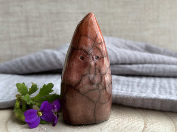 Raku ceramic sculpture of a tall, pointy gnome glazed in a bottom-to-top gradient of brown to bordeaux red to warm orange.