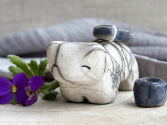 Raku ceramic white bear sculpture with a kind, gentle face. It carries a blue ceramic crescent moon on its back and has a little blue bowl too.