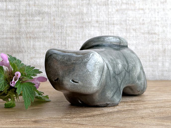 Little raku ceramic cat spirit kami sculpture glazed in grey. It has a kind, gentle, sleepy face, and its tail is curled over its back on the left.